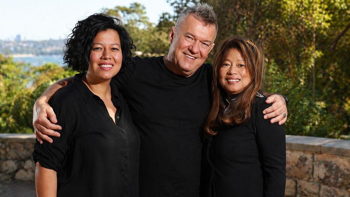 Jimmy Barnes standing with Jane Mahoney and daughter Mahalia Barnes smiling together in an outdoor setting