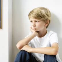 Forlorn boy sitting in a corner thinking