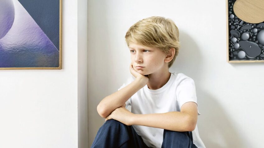 Forlorn boy sitting in a corner thinking