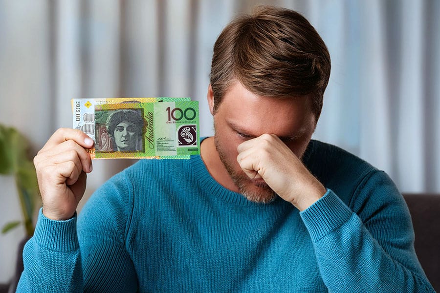 Man with fist to head holding up 100 dollars