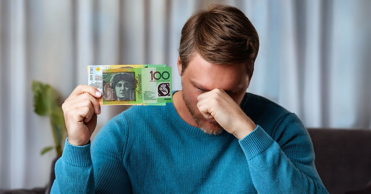 Man with fist to head holding up 100 dollars